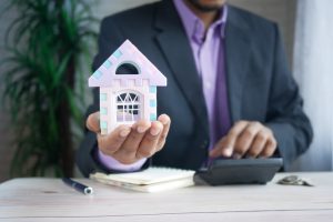 Real estate agent holding a demo house in his left hand